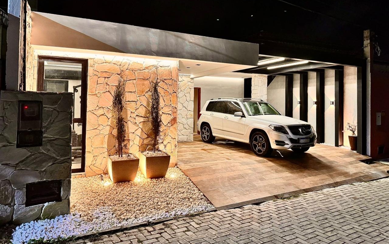 Resultado final — fachada residencial reformada com pedra e iluminação noturna